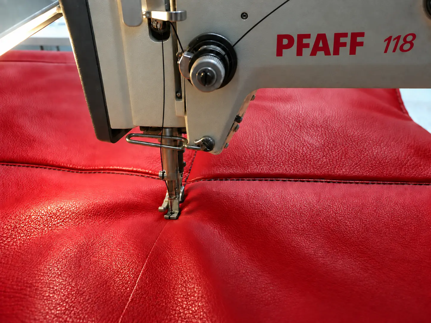 Pfaff 118 Industrienähmaschine näht rotes Leder mit schwarzer Ziernaht.