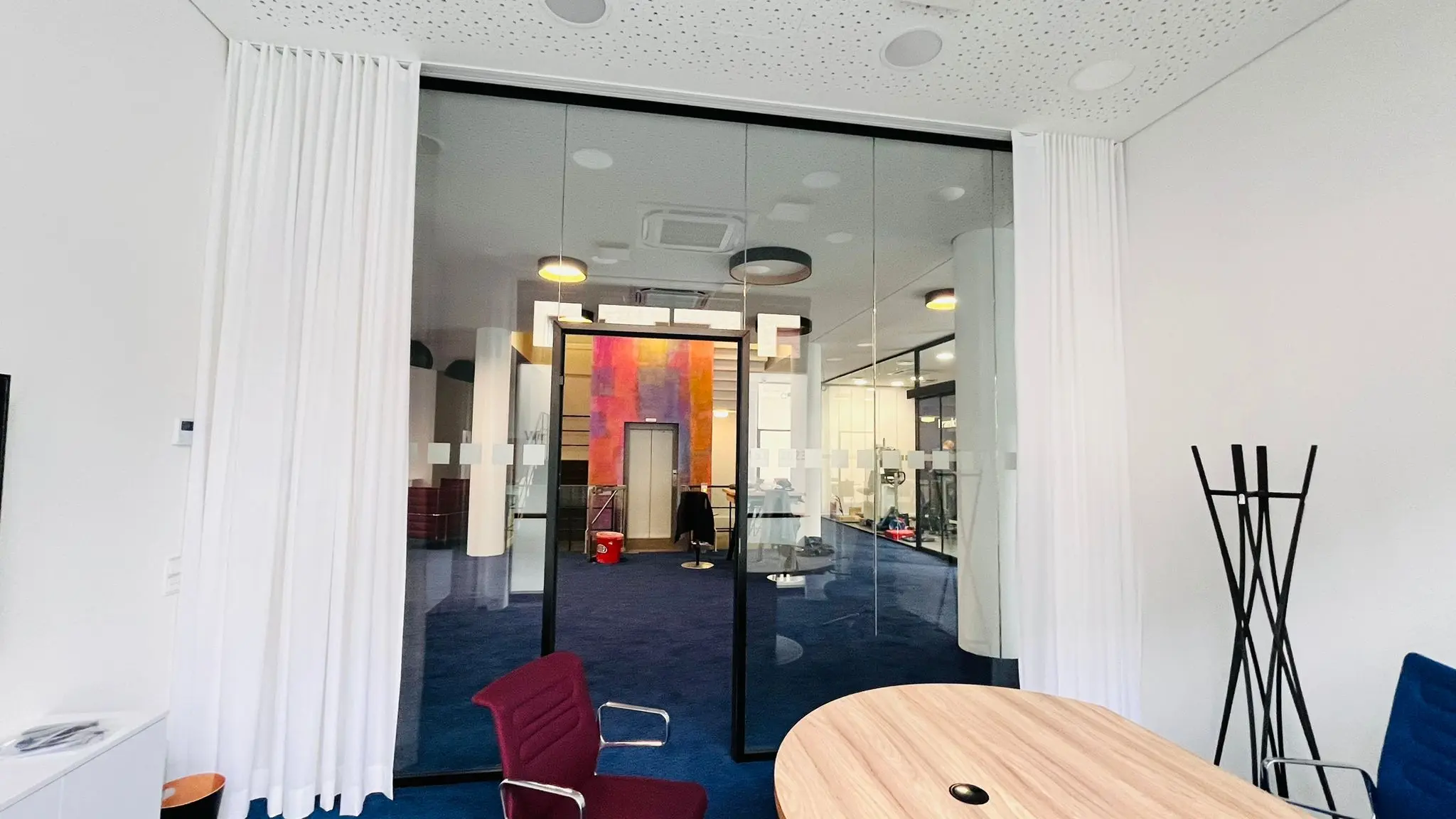 Weiße Objektvorhänge an einer gläsernen Raumtrennung der Frankfurter Volksbank